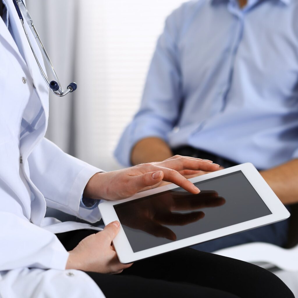 Female doctor using touchpad or tablet computer while consulting man
