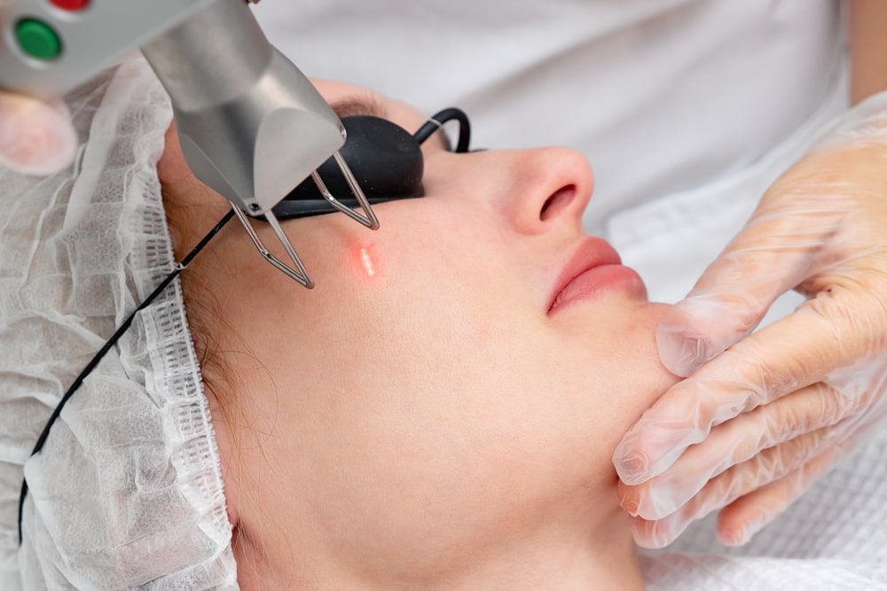 rejuvenation procedure on woman face wearing protective glasses